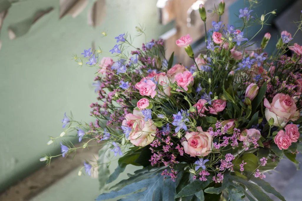 Pastelowy bukiet z różami, goździkami i niebieskimi kwiatami sezonowymi – przykład kompozycji premium powyżej 200 zł