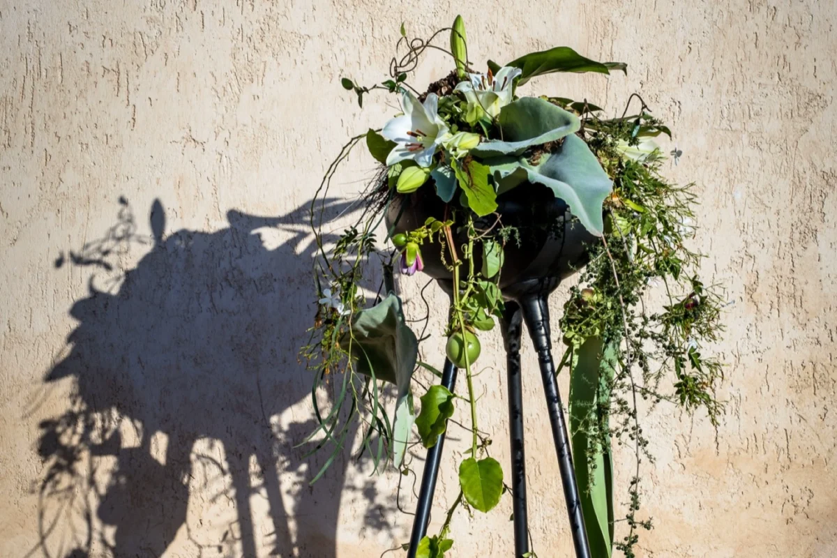 Nowoczesna kompozycja florystyczna z zielenią i białymi kwiatami na stojaku – przykład florystyki łączącej rzemiosło i artyzm