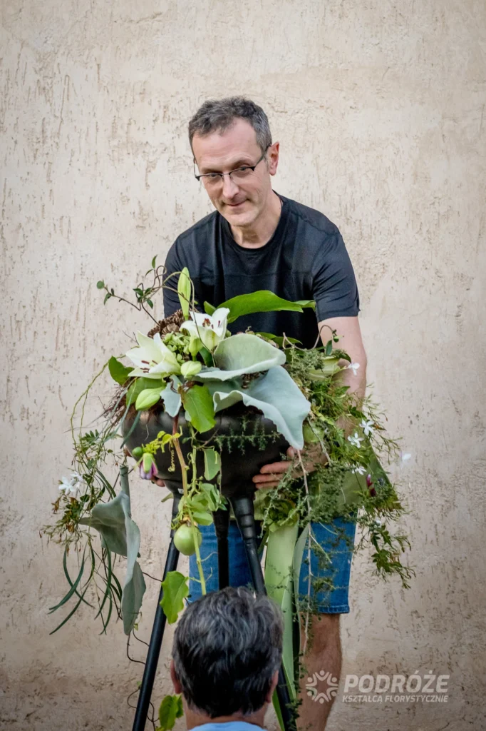 Florysta pracuje nad kompozycją kwiatową na stojaku podczas warsztatów florystycznych