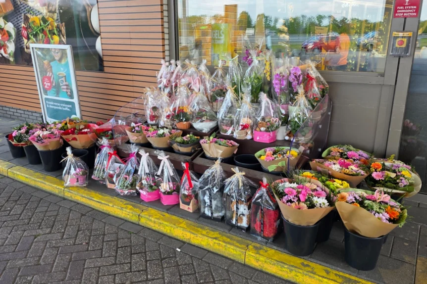 Bukiety i kompozycje kwiatowe oferowane przed sklepem na stacji benzynowej w Holandii, pokazujące popularność spontanicznych zakupów kwiatów.