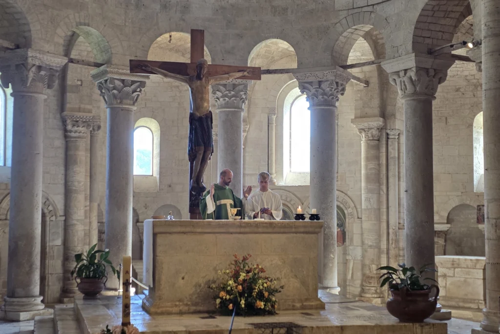 Ołtarz w romańskim kościele z niewielką kompozycją z żywych kwiatów podkreślającą prostotę i charakter liturgii.